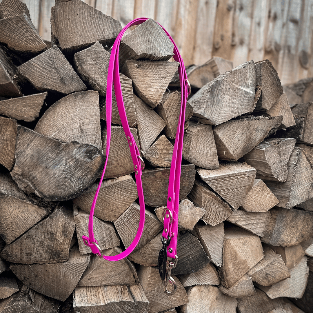 Berry Pink multi-way hands-free BioThane dog lead with a heavy-duty black lockable carabiner and O-ring placed on a wooden stack