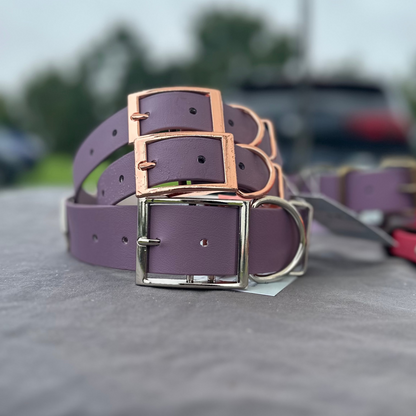 A stack of mauve purple dog collars resting on top of each other with a blurred background.